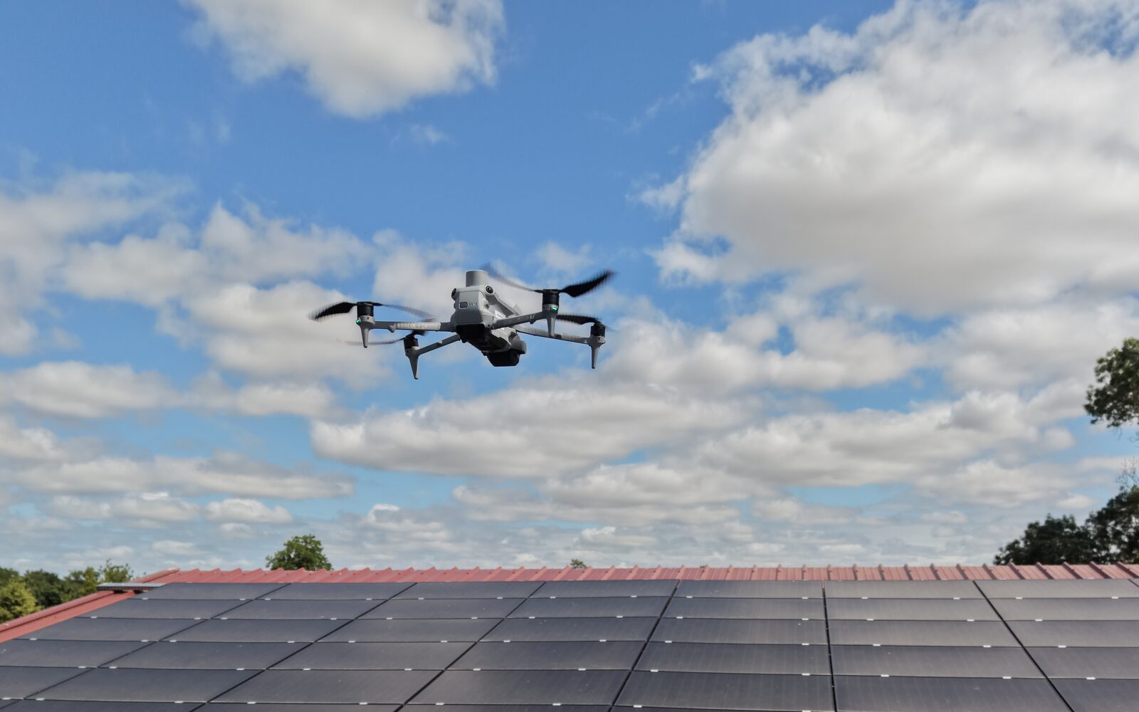 Drone d'inspection en vol au-dessus d'une toiture photovoltaïque sous un ciel dégagé