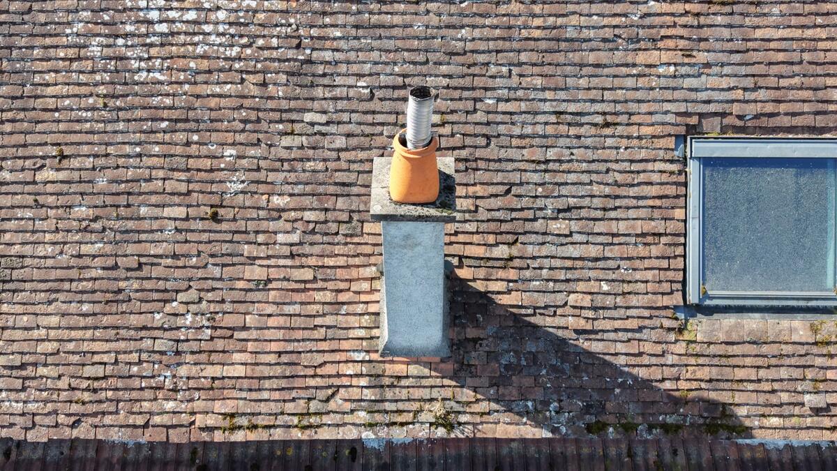 Souche de cheminée maçonnée et fenêtre de toit vues du dessus par drone